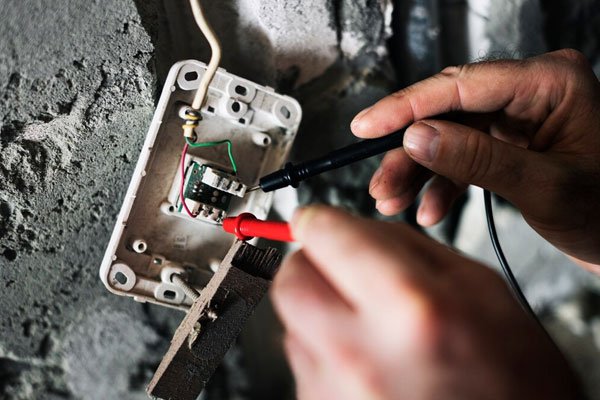 Electrician testing electrical wiring with a multimeter